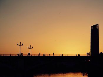 People walking on bridge at sunset