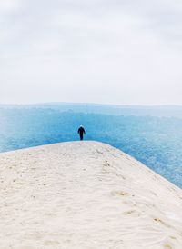 Rear view of man walking on landscape against sky