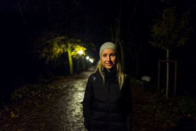 Portrait of smiling woman standing on road at night