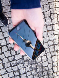 Close-up of hand holding smart phone with fernsehturm on screen