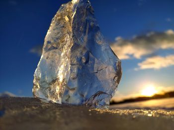 Close-up of frozen rock on land against sky during sunset