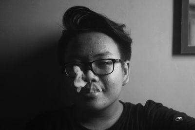 Close-up portrait of teenage boy wearing eyeglasses at home