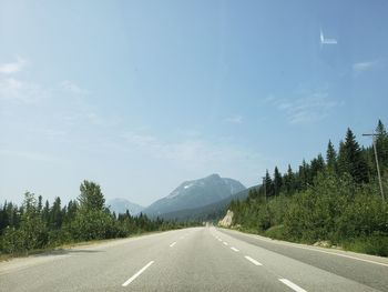 Road by trees against sky