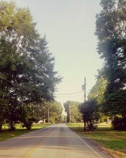 Road amidst trees and city against sky
