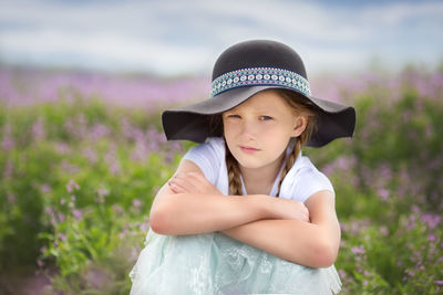 Young woman wearing hat standing against plants