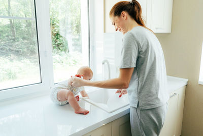 Side view of mother and daughter against window