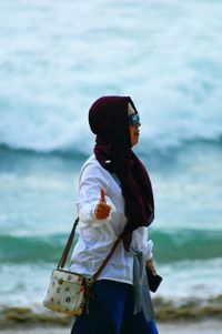 Woman standing at beach against sky