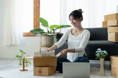 Side view of young woman sitting on table at home