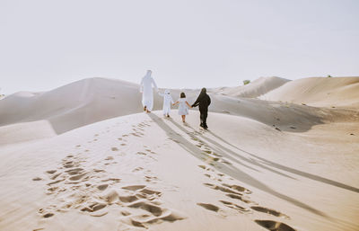 Rear view of family walking on sand dune
