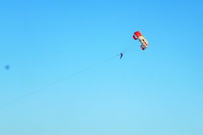 Low angle view of paragliding against clear blue sky