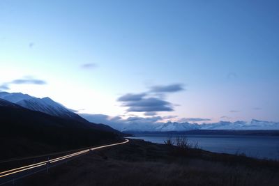 Road by sea against sky during sunset