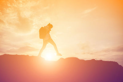 Silhouette person standing on mountain against sky during sunset