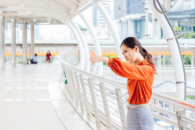 Young woman using phone while standing in corridor