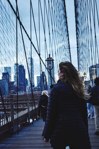 Low angle view of woman standing on bridge against sky