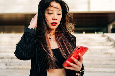 Long hair brunette asian woman using mobile phone in the street