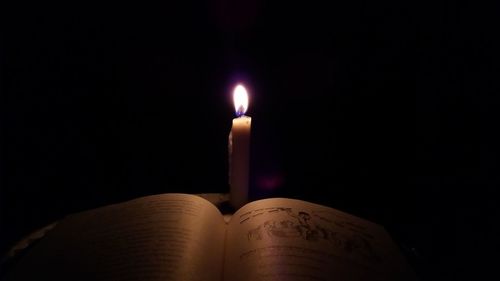 Close-up of lit candle in darkroom