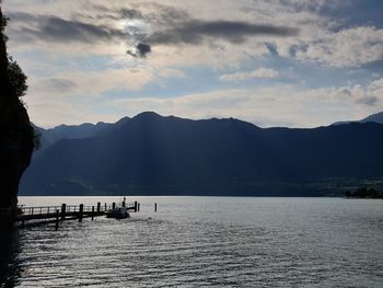 Scenic view of lake and silhouette mountains against sky