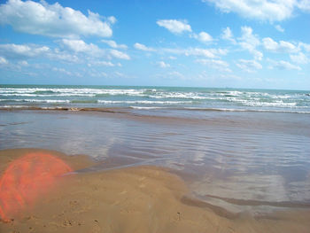 Scenic view of beach against cloudy sky