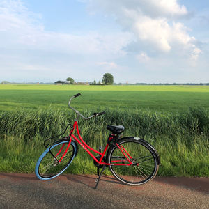 Bicycle parked on field against sky