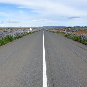 Road amidst field against sky