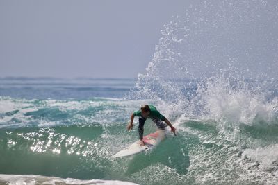 Man surfing in sea against sky