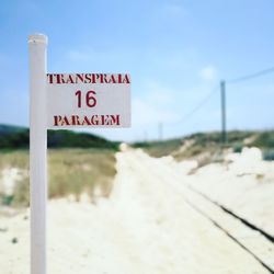 Close-up of road sign on beach against sky