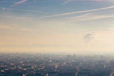 Aerial view of city and air pollution against sky during sunset