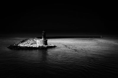 Lighthouse by sea against sky at night