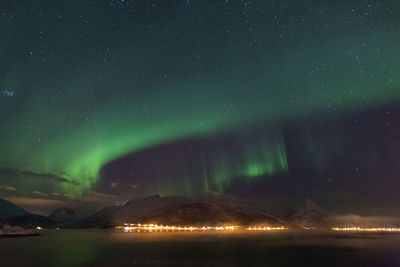 Idyllic shot of aurora borealis over lake against sky at night
