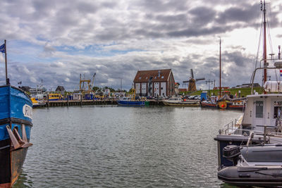 Sailboats moored at harbor against sky