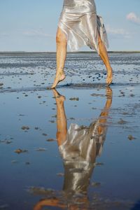 Low section of woman standing at beach