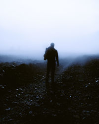 Rear view of man standing on land against sky