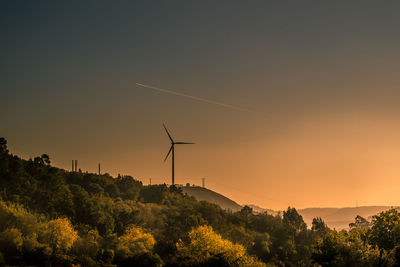 Silhouette wind turbines on landscape against sky during sunset