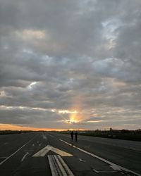 Man standing on road against sky during sunset