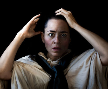 Portrait of woman with arms raised against black background