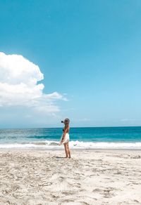 Full length of woman standing at beach against sky during summer