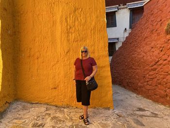 Full length of woman standing against wall in building orange and red 