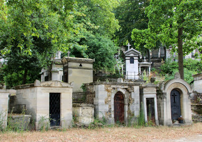 Exterior of old graves by trees on graveyard