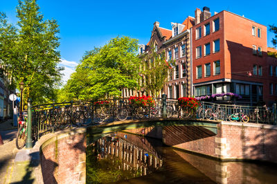 Canal by buildings in city against sky