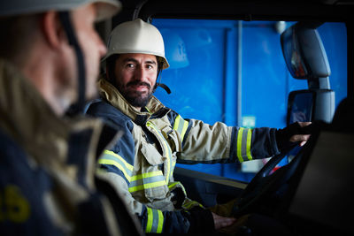 Firefighter looking at coworker while sitting in fire truck