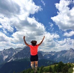 Rear view of woman standing on mountain against sky