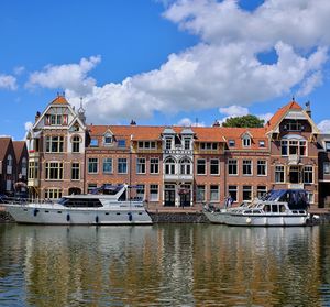 Buildings by river against sky