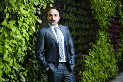 Businessman in suit standing against plants
