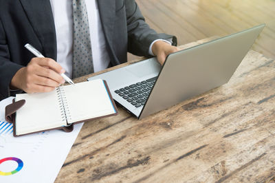 Midsection of man using mobile phone while sitting on table