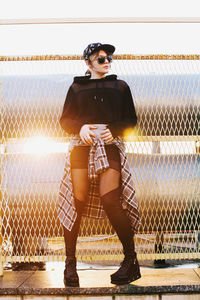 Portrait of young woman standing against chainlink fence.construction net. korean fashion. european.