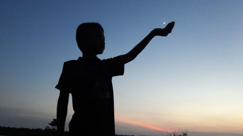 Low angle view of silhouette boy against clear sky