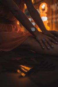 Midsection of woman sitting in illuminated city at night