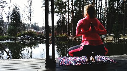 Rear view of woman with arms raised against trees