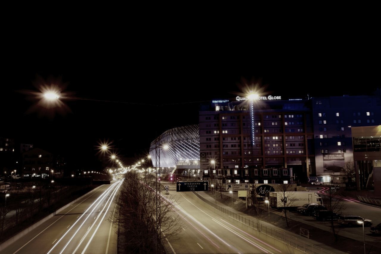 illuminated, night, city, transportation, architecture, building exterior, road, built structure, light trail, street, car, traffic, long exposure, city life, street light, city street, land vehicle, motion, high angle view, clear sky