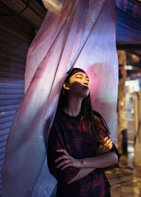 Midsection of young woman standing against wall